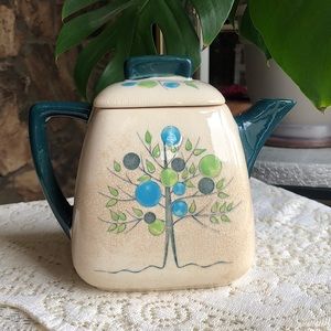 Vintage teapot with tree and bobble design. Greens, blues, white color